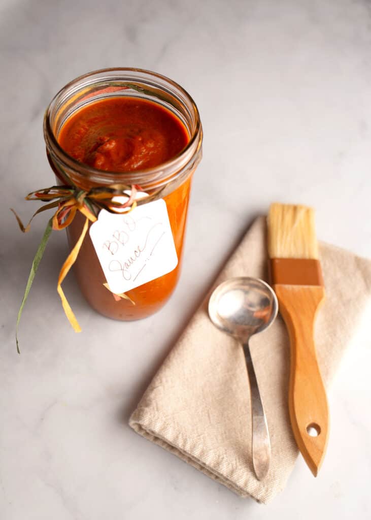 Jar of Franklin-inspired BBQ Sauce with a brush and ladle
