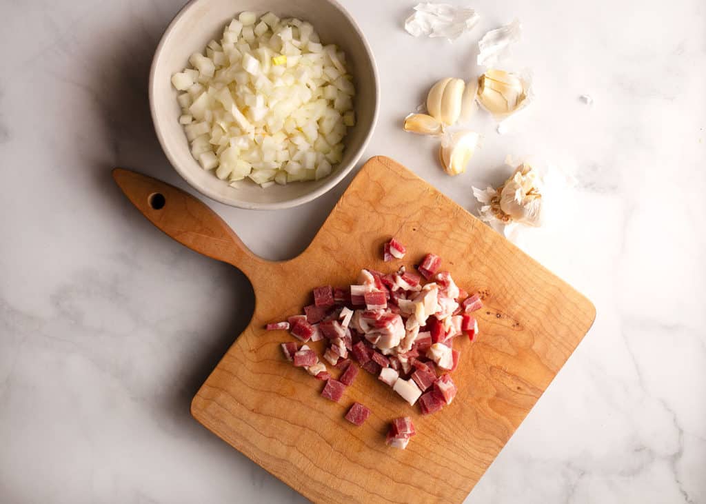 Chopped bacon on a cutting board, onions, garlic