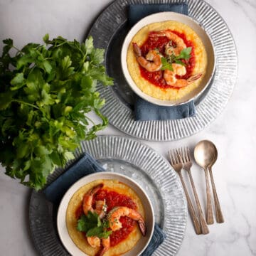 Two servings of Shrimp & Grits in pottery bowls