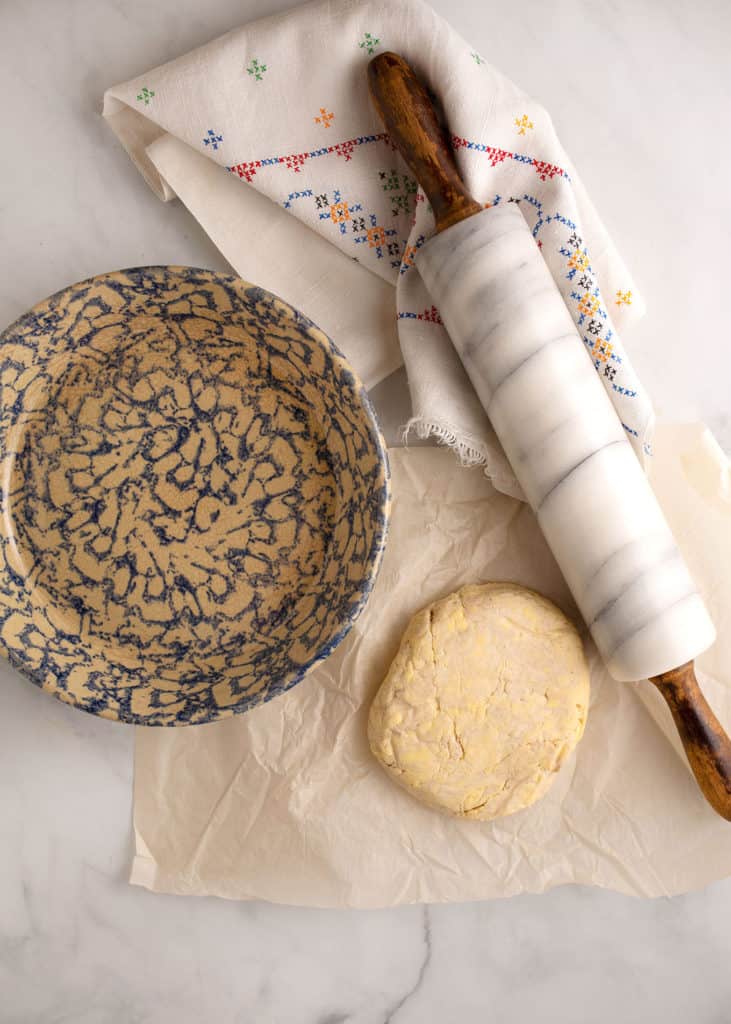 Pie crust next to a pie plate and rolling pin