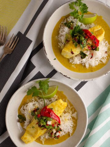 Two pottery bowl with rice topped with Coconut Curry Halibut