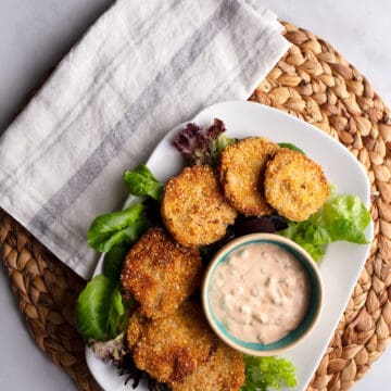 Fried Green Tomatoes on a platter lined with lettuce with Remoulade Sauce in a small bowl