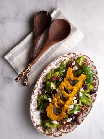 Roasted Delicata Squash Salad on a platter with serving tools beside