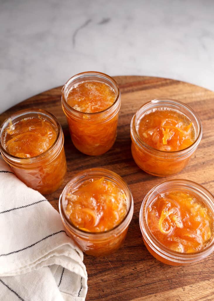 Five half-pint jars of Orange Marmalade on the cutting board