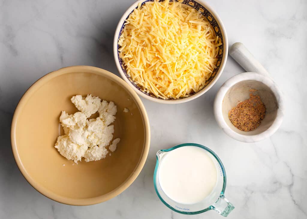 Grated cheese, ricotta, buttermilk, and spices in bowls