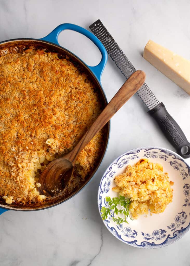 Baking dish with baked buttermilk macaroni n' cheese and a serving in a bowl beside