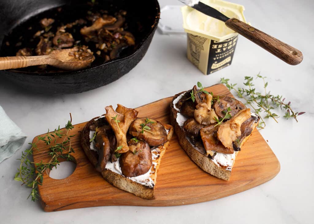 Two Mushroom Tartines with Goat Cheese on a board with thyme sprigs