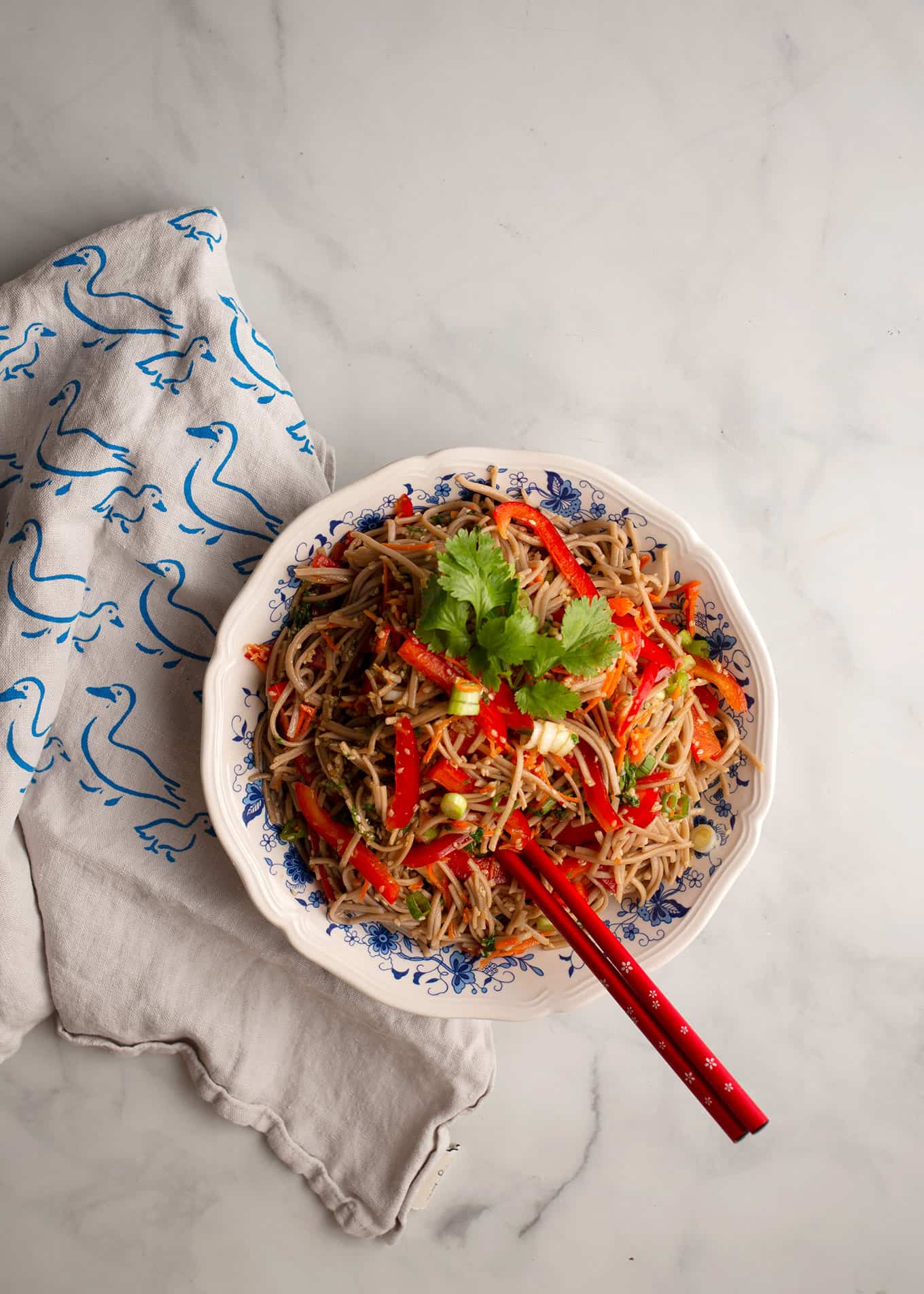 Sesame Noodle Salad in a blue and white bowl with red chopsticks