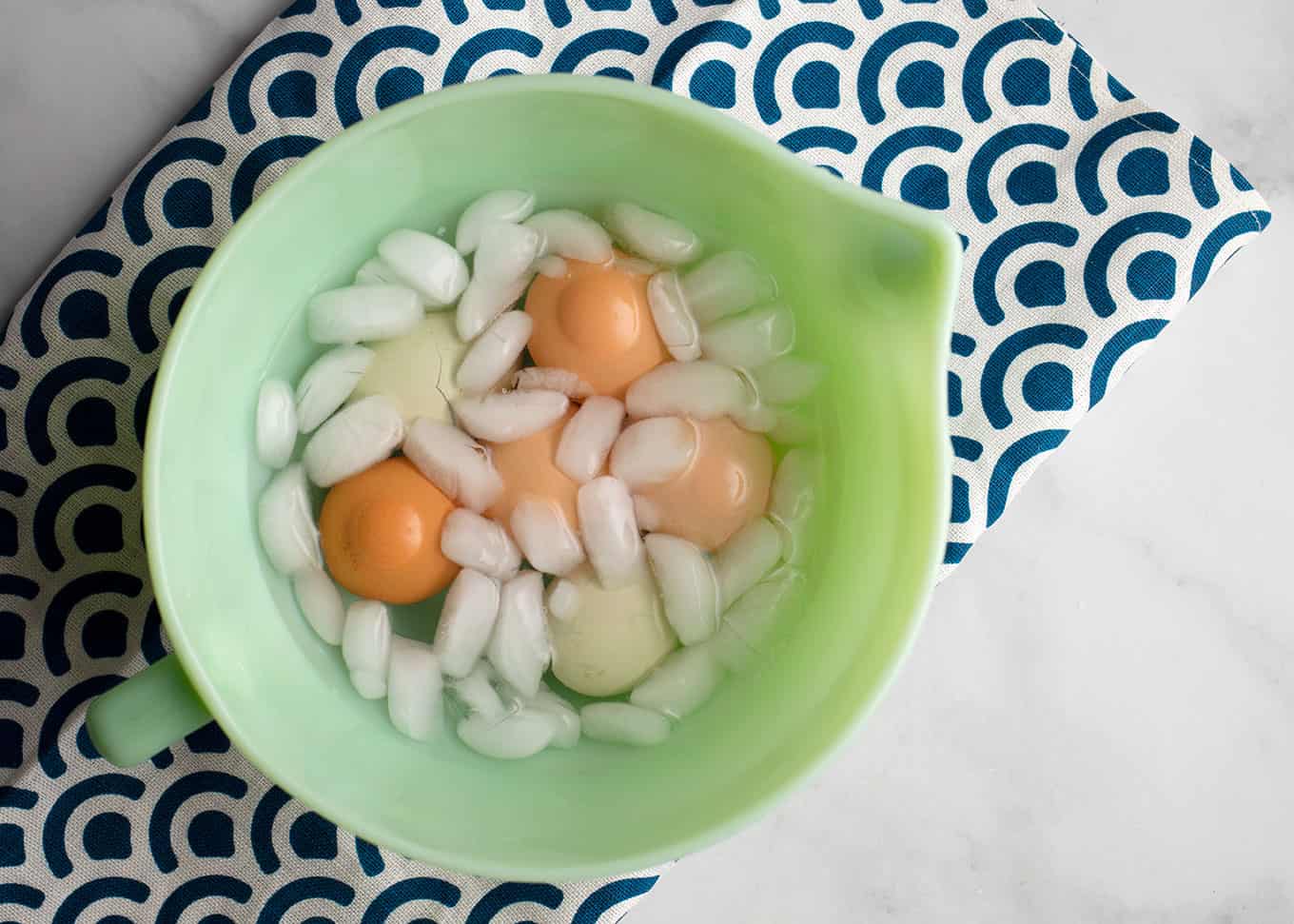 Cooked eggs in ice water in a jadeite bowl