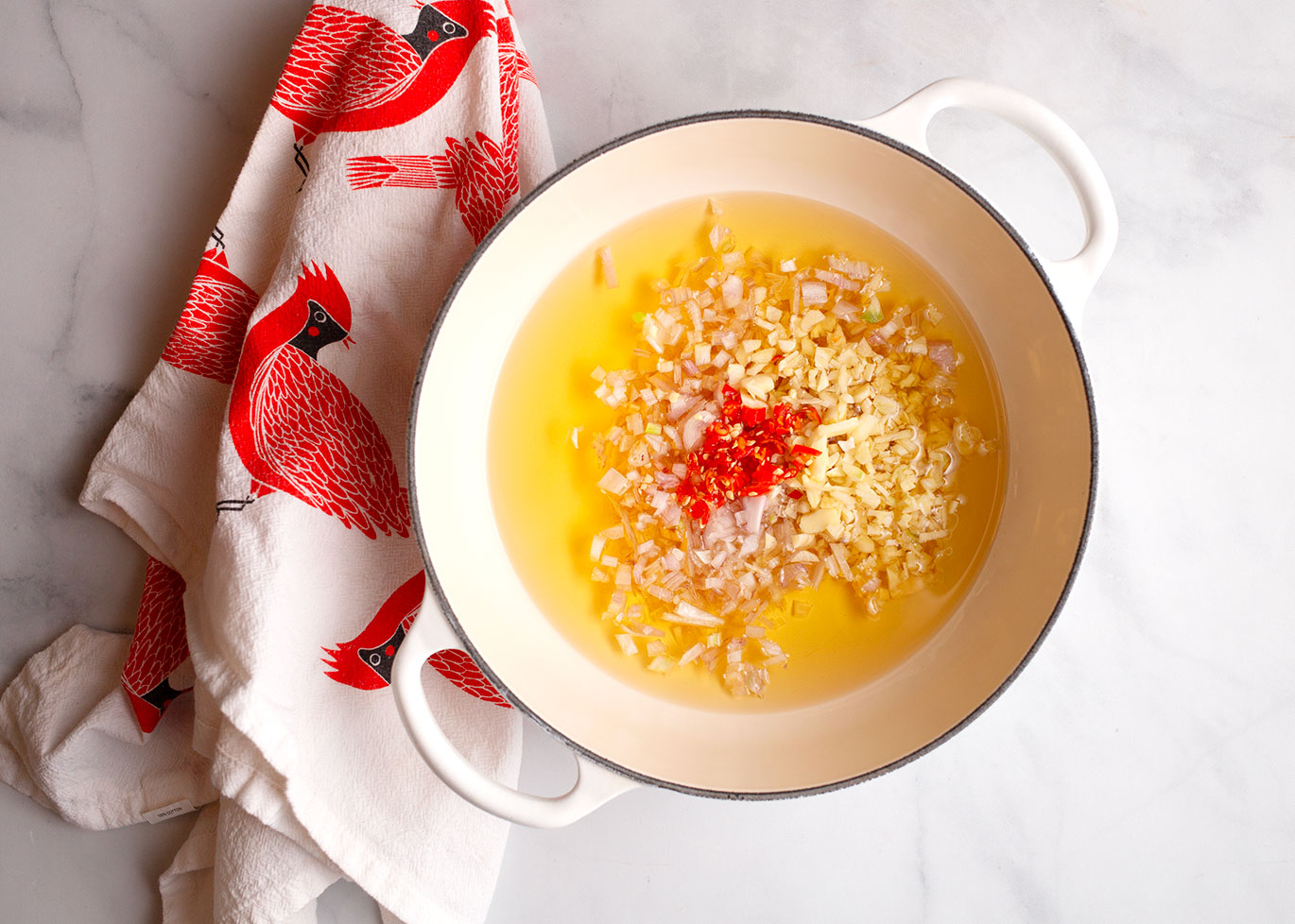 Chopped shallot, garlic, and peppers in a pot with oil