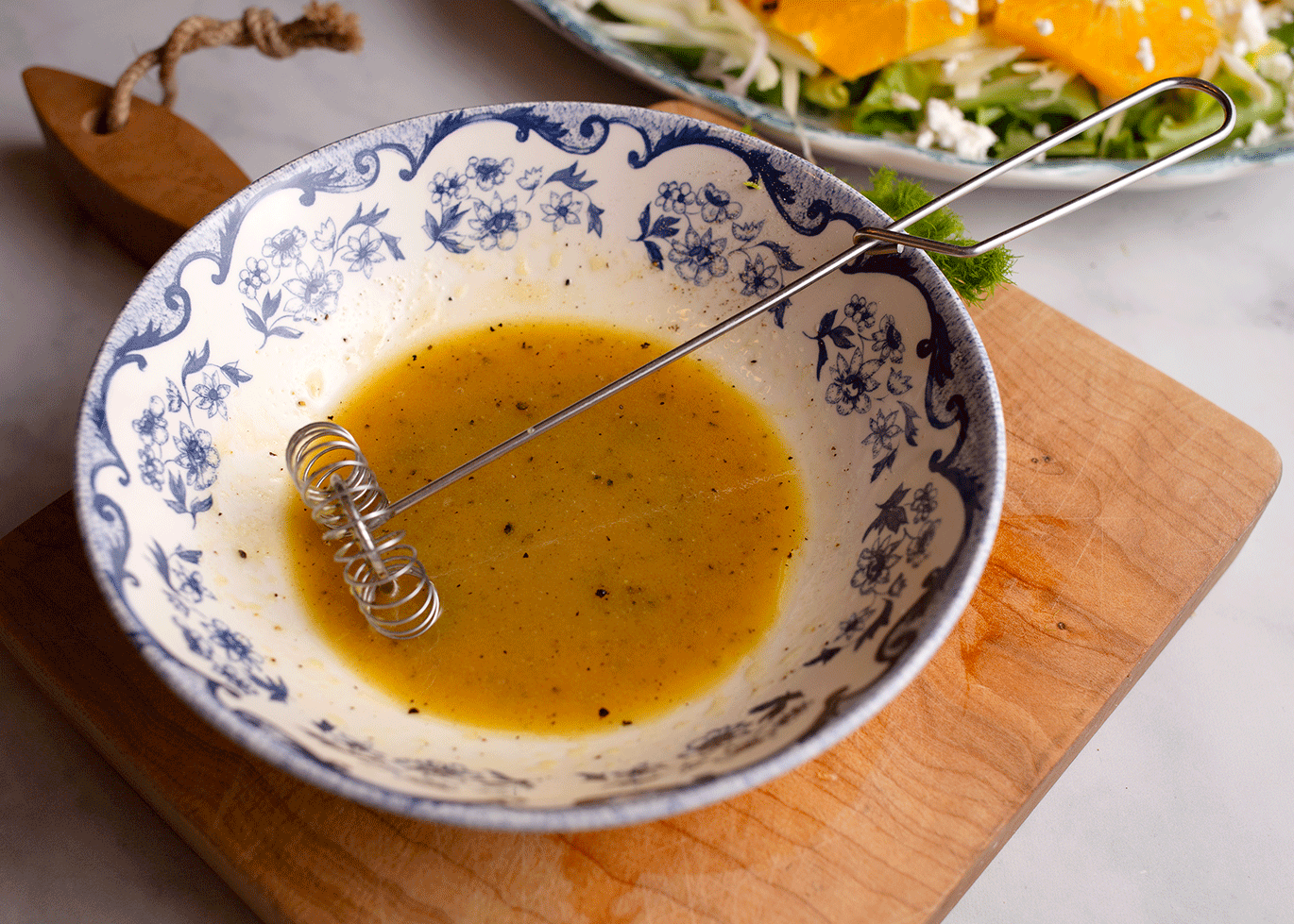Whisked vinaigrette ingredients in a blue & white bowl.