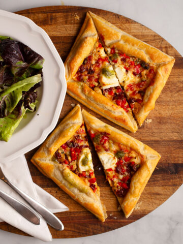 4 Cheese and sundried tomato tarts on a board with a side salad
