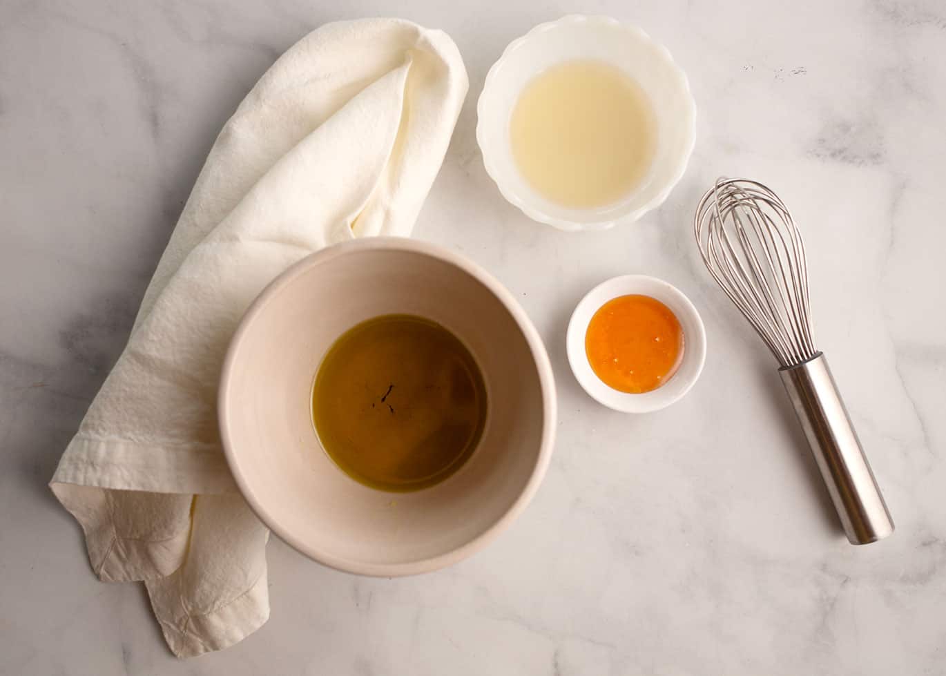 Olive oil, champagne vinegar, and honey with a whisk for vinaigrette.