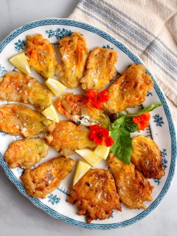 Lemon Ricotta Stuffed Zucchini Flowers on a blue and white platter